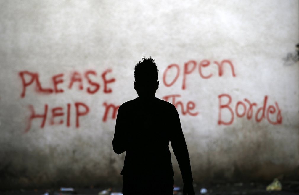 یکی از مهاجرین در حال قدم زدن در یکی از انبارخانه های متروکه در بلگراد، صربستان. تصویر از AP.