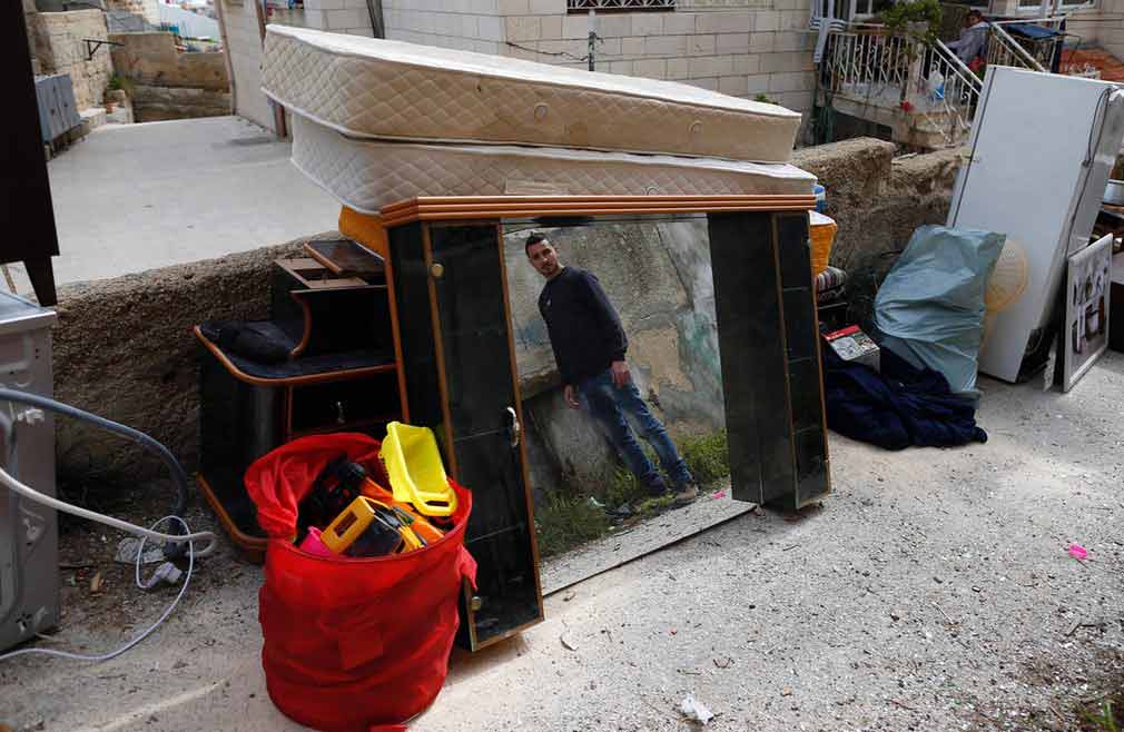 مرد فلسطینی بعد از آنکه خانه شان توسط اسکواترهای اسرائیلی فروریخته شد در کنار وسایل خانه خود ایستاده است. تصویر از AFP