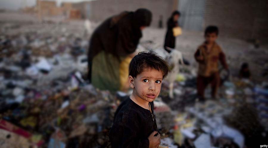 بانوی افغان و کودکان‌اش در حال جستجو در میان زباله ها