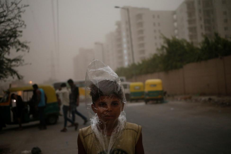 A young boy uses a plastic bag to protect himself from a dust storm in New Delhi, May 23, 2016. REUTERS/Anindito Mukherjee