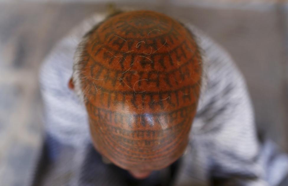 Chanda Ram, 72, a follower of Ramnami Samaj, who has tattooed the name of the Hindu god Ram on his entire face and head, poses for a picture inside his house in the village of Chapora, in the eastern state of Chhattisgarh, November 15, 2015. REUTERS/Adnan Abidi