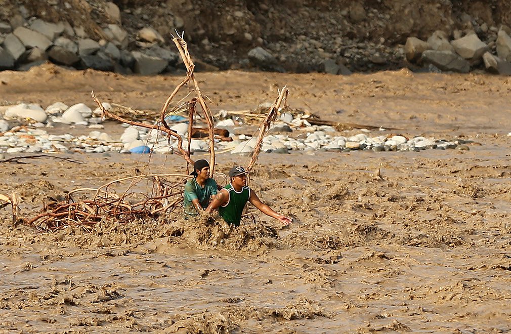 دو پسر جوان در حال عبور کردن دریای ریماک در شهر لیمای پیرو. تصویر از Reuters.