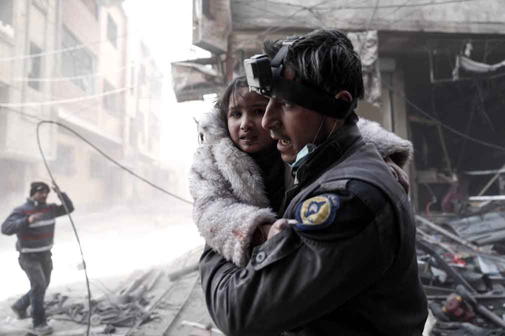 یکی از سربازان نیروهای دفاعی غیر دولتی سوری، دختر خردسالی را که در اثر حمله هویی مجروح شده است به آغوش گرفته. تصویر از Getty