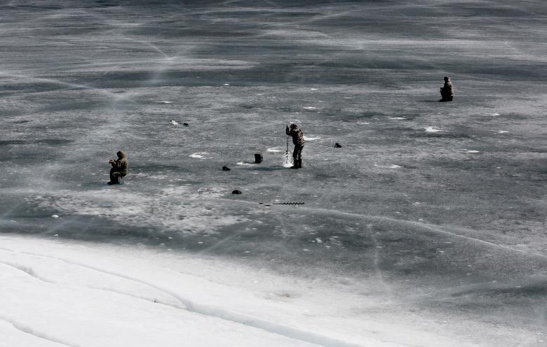 ماهی‌گیران روس حین ماهی‌گیری از دریای که تمام آن‌را یخ بسته است / عکس: رویترز