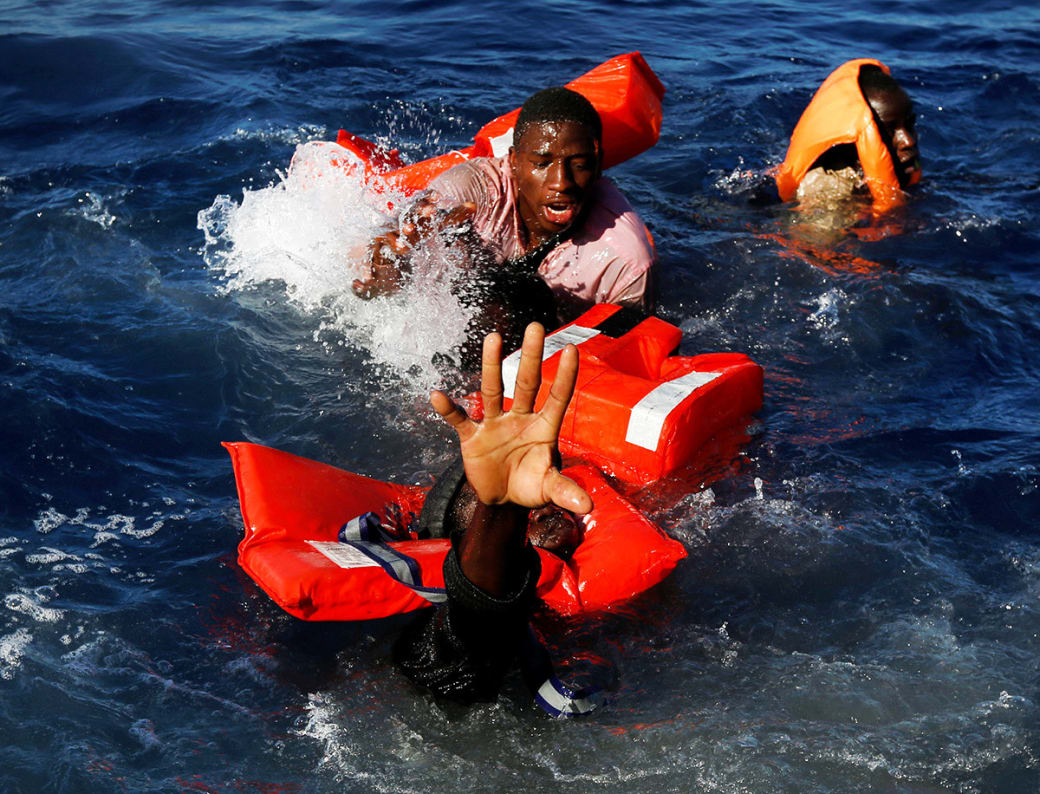 مهاجران در تلاش به دست‌آوردن جلیقه‌های نجات؛ این تصویر پس از غرق‌شدن قایق لاستیکی آنان و عملیات نجات توسط سازمان غیر دولتی مالت در آب‌‎های مدیترانه، گرفته شده است. / عکس: رویترز
