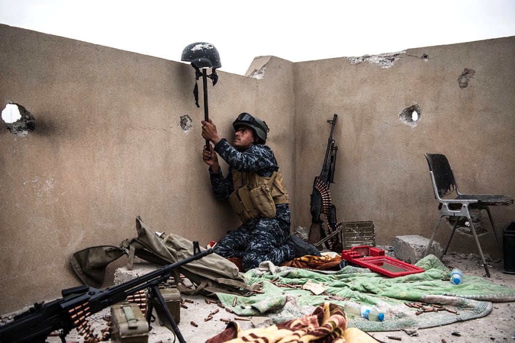 این تصویر توسط کارل کورت زمانی ثبت شده که یک سرباز فدرال عراقی با بلند کردن کلاه یکی از همرزمان خود، در تلاش جلب تیراندازی تک‌تیرانداز داعشی بوده است. / عکس: گیتی