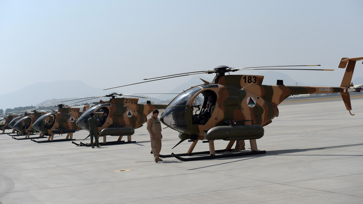In this photograph taken on September 29, 2016, an Afghan pilot stands next to a line of US-made MD-530 Helicopters in Kabul.  Under pressure from the Taliban, Afghanistan's military is increasingly relying on the country's young air force, and, together with Western allies, is speeding up its training of pilots and ground controllers in order to strike the enemy. / AFP PHOTO / SHAH MARAI