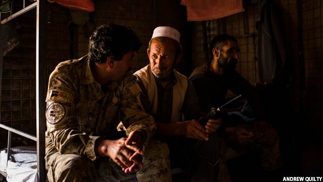 غلام سخی در حال صحبت با یک عضو ارتش ملی افغانستان و جنگجویان پولیس محلی افغان داخل یکی از پایگاه های پولیس محلی 