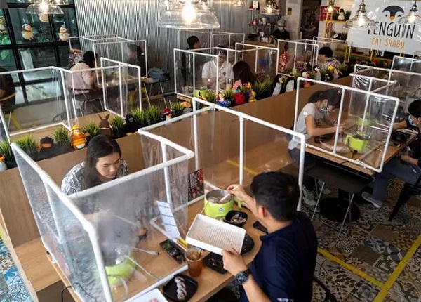 رستورانی را در بانکوک نشان می‌دهد که مردم با رعایت فاصله غذا می‌خورند.